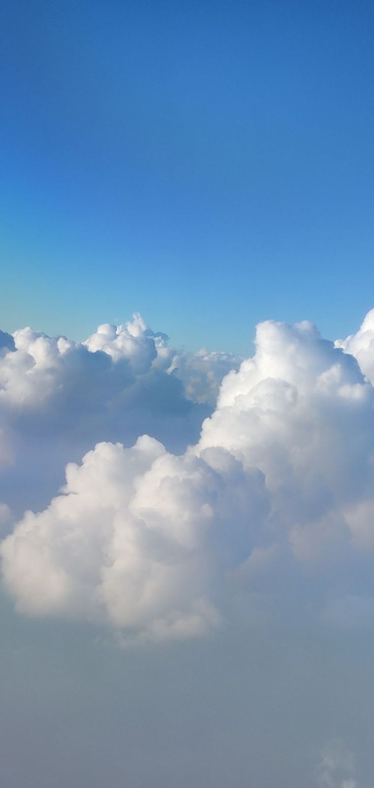 an airplane is flying high in the sky above some fluffy white clouds and blue skies