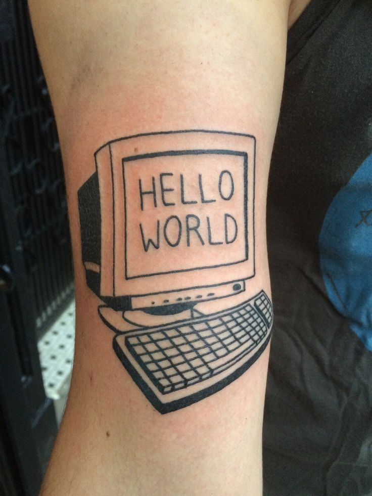 a tattoo that says hello world on the side of a person's arm, with a keyboard in front of it