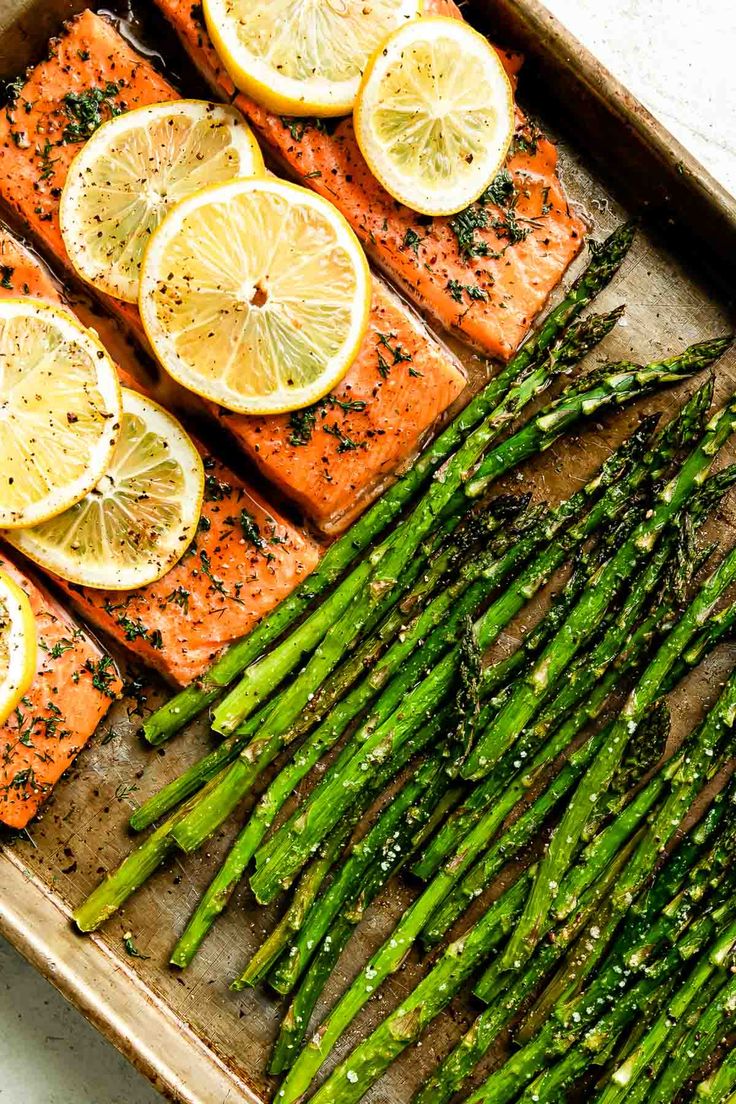 salmon and asparagus on a tray with lemons