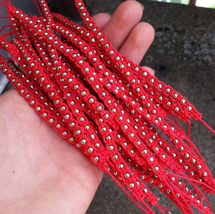 a hand holding a red string beaded bracelet with lots of small beads on it