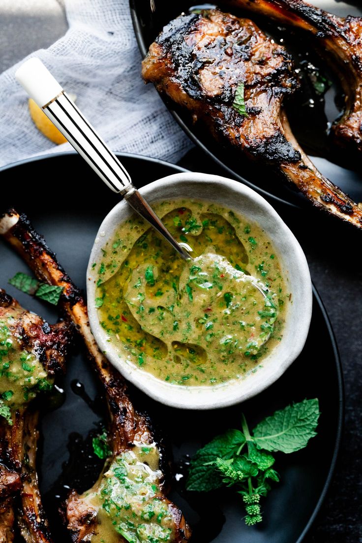 grilled lamb chops with pesto sauce on a black plate