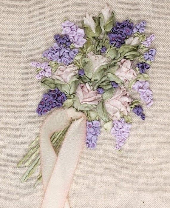 a bouquet of purple flowers with a white ribbon tied around it on a piece of cloth