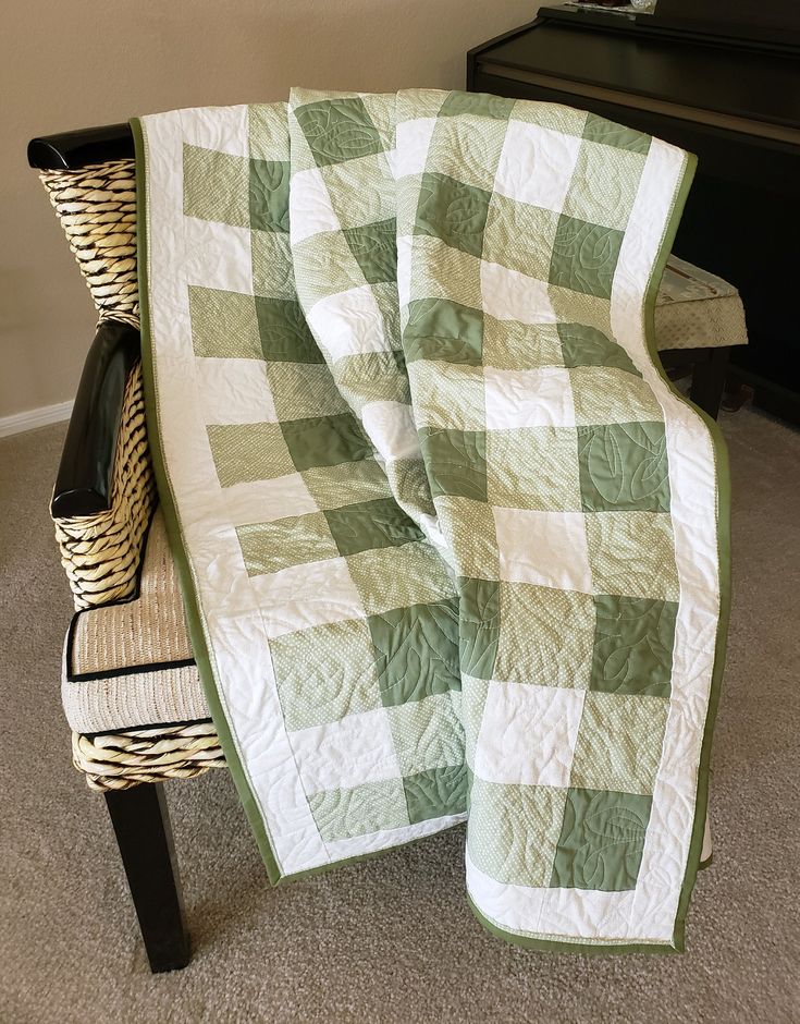 a green and white blanket sitting on top of a chair next to a black piano