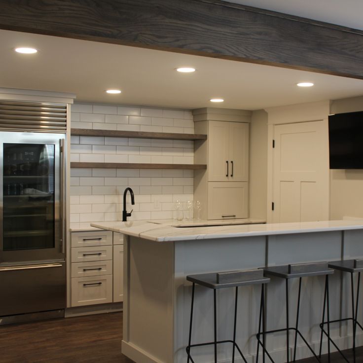 a kitchen with an island and three bar stools in front of the counter top