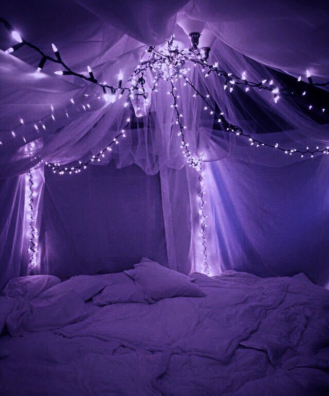 an unmade bed with lights on the ceiling and canopy over it in a dark room