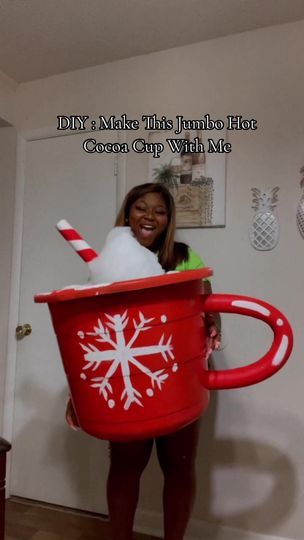 a woman holding a large red cup with snowflakes on it