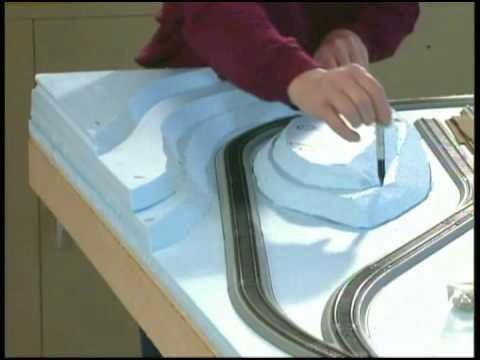 a person is working on a model train track with a pen and paper in front of them