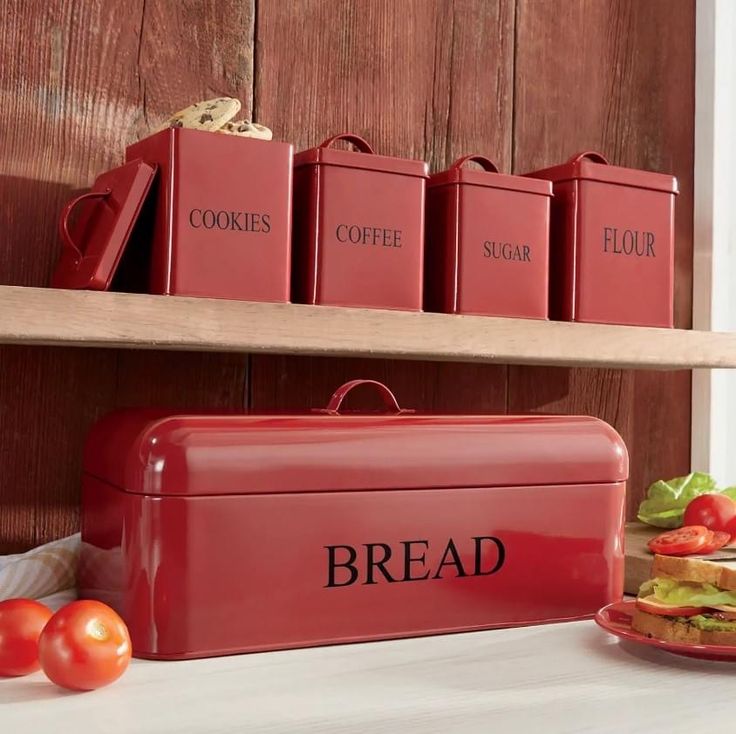 a red lunch box sitting on top of a counter next to some tomatoes and lettuce