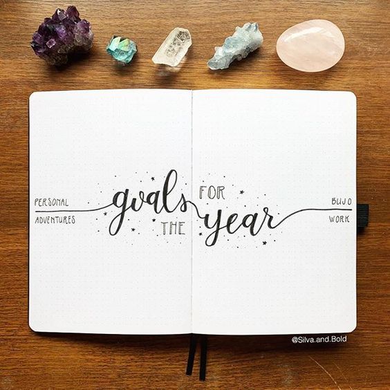 an open notebook with the words goals for the year written in cursive writing