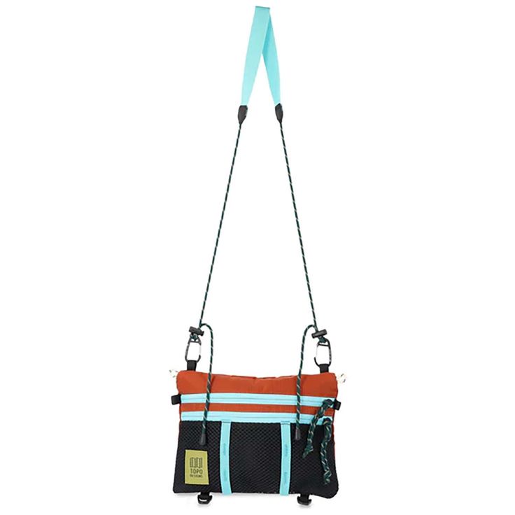 an orange, blue and black handbag hanging from a hook on a white background