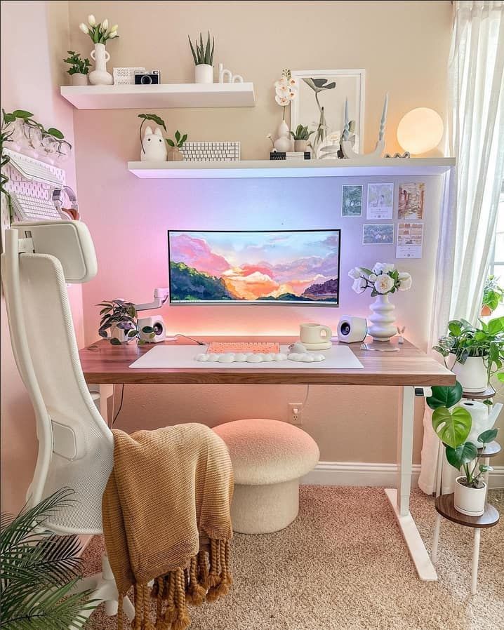 a desk with a computer on it and some plants in the corner next to it