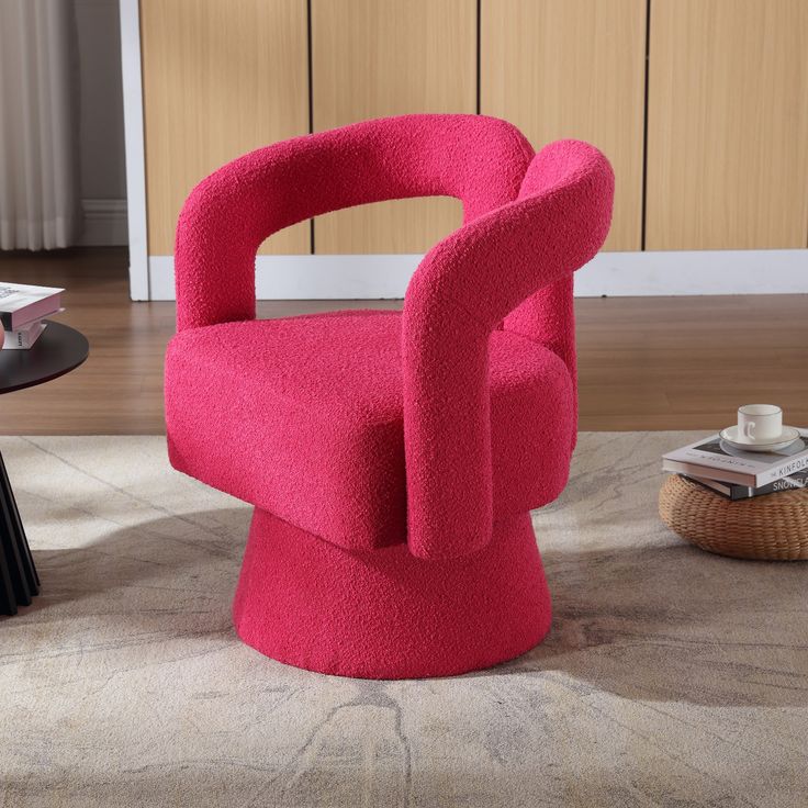 a pink chair sitting in the middle of a living room next to a coffee table