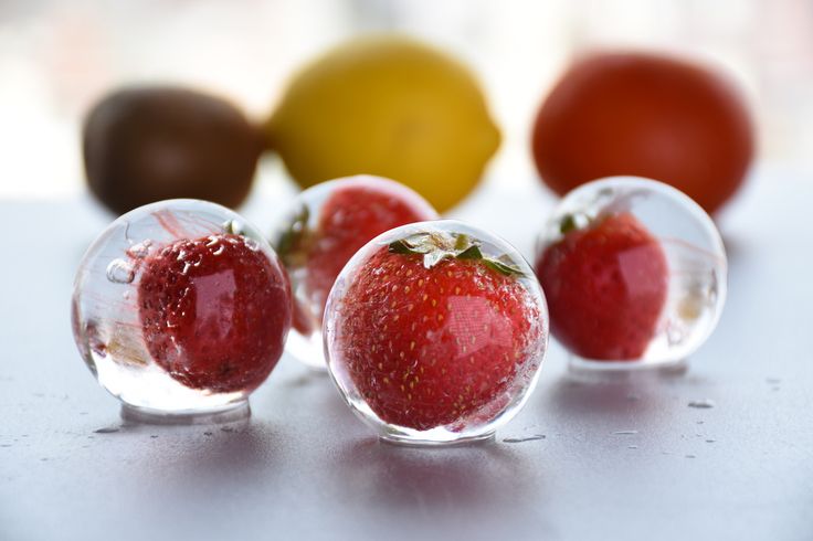 four glass balls with strawberries in them