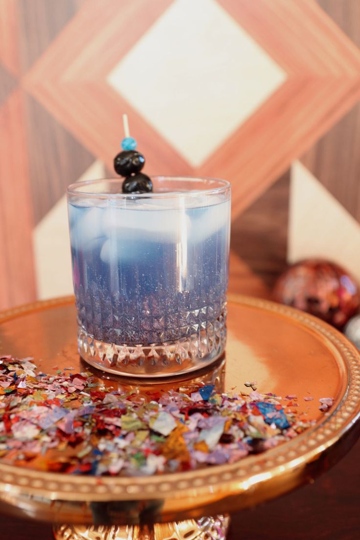 a candle sitting on top of a golden tray filled with confetti and sprinkles