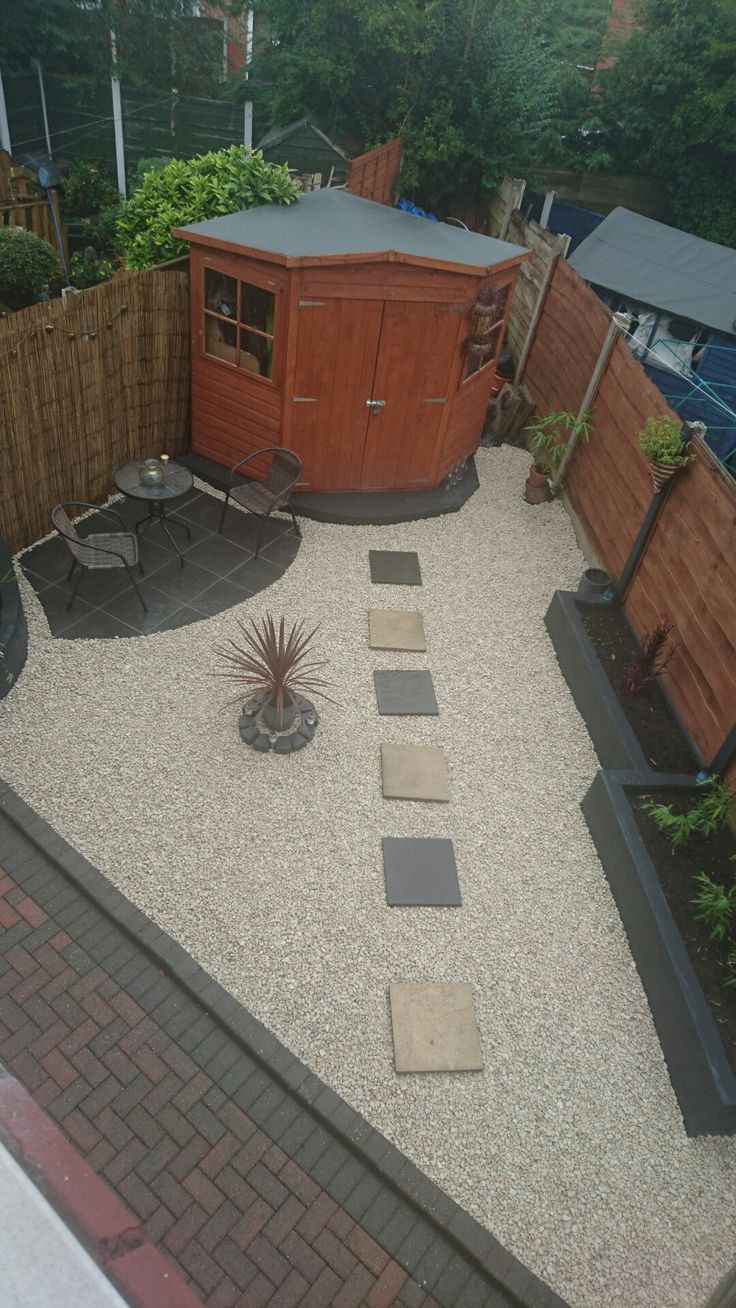 a small backyard with a hot tub and gravel path leading to the back yard area