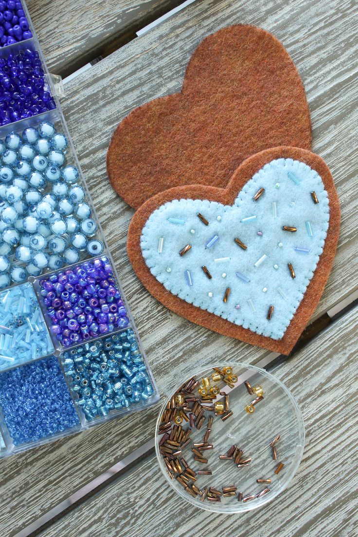 a heart shaped cookie sitting on top of a wooden table next to beads and sprinkles