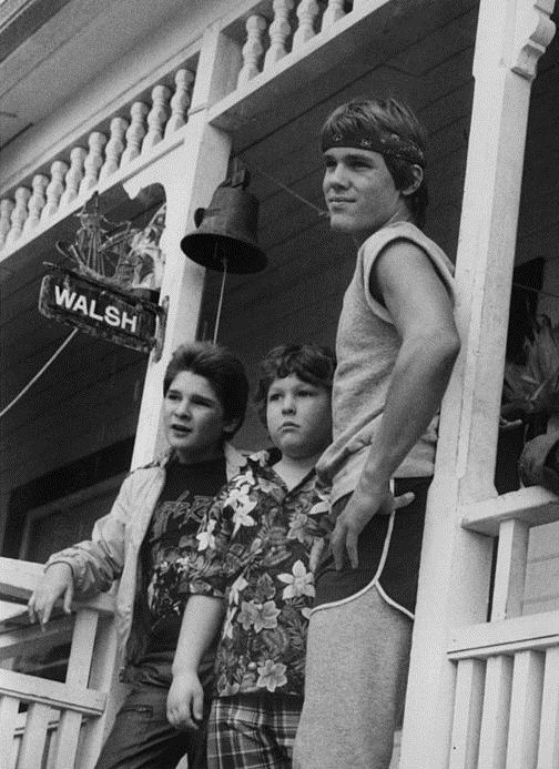 three young men standing on the porch of a house in front of a sign that says walish