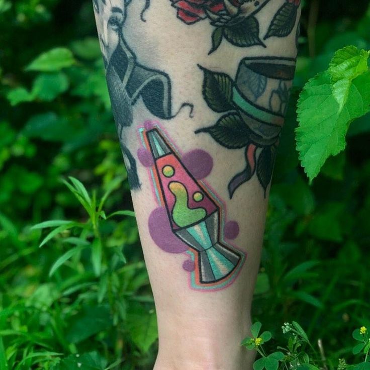 a person's leg with tattoos on it and some flowers in the grass behind them