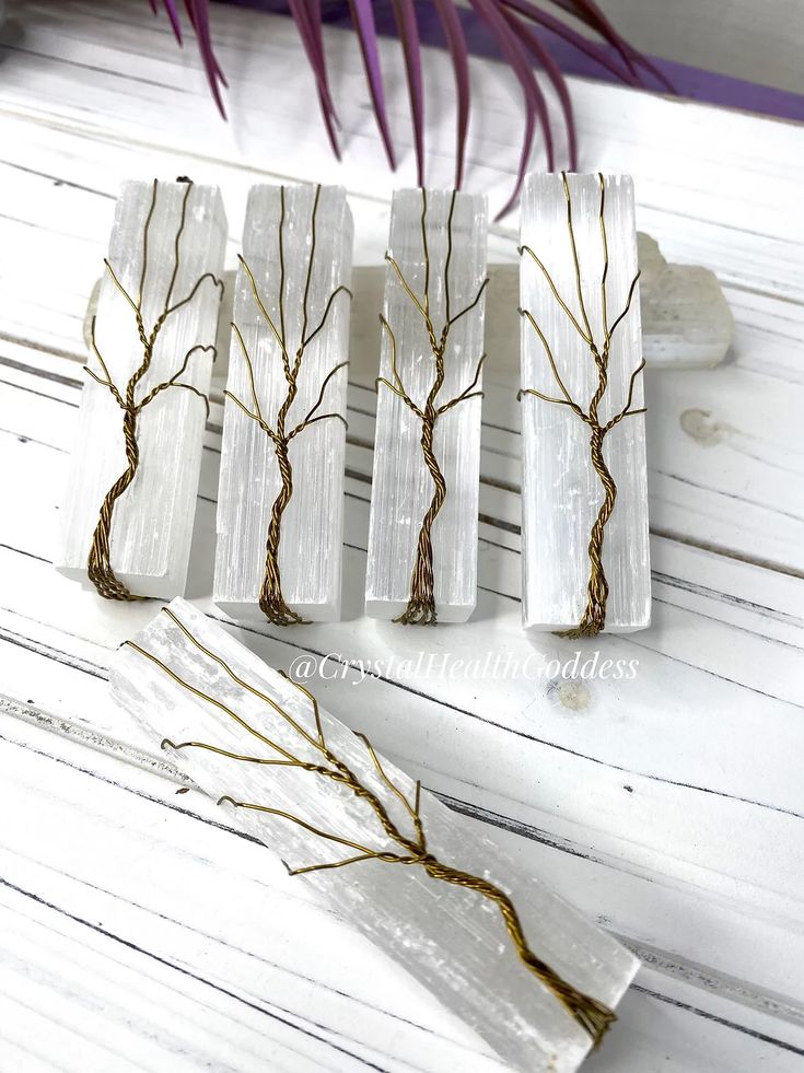 four pieces of white marble with tree branches on them, sitting on a wooden table