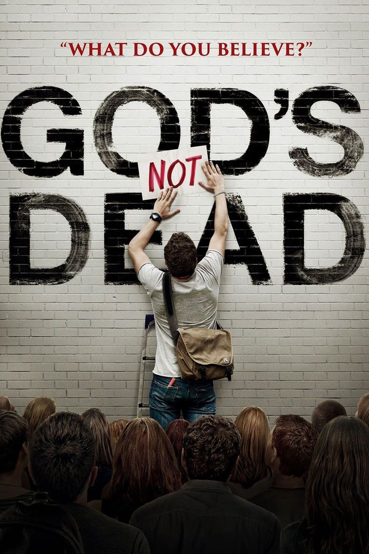 a man standing in front of a brick wall with the words god's not dead written on it