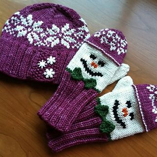 two knitted snowmen hats and mittens sitting on a wooden floor next to each other