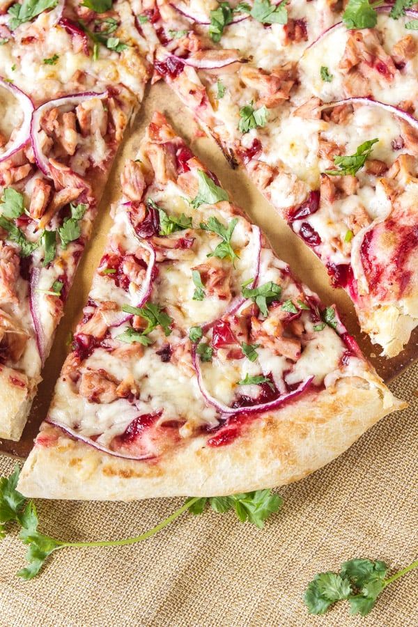 a pizza with meat, cheese and veggies cut into slices on a table