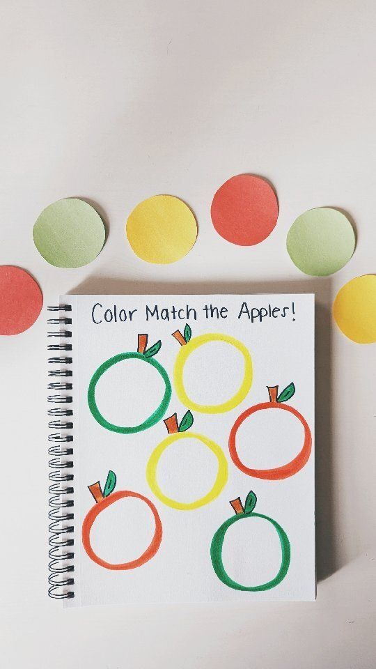 a spiral notebook with colored paper apples and circles around it on a white surface, surrounded by confetti balls