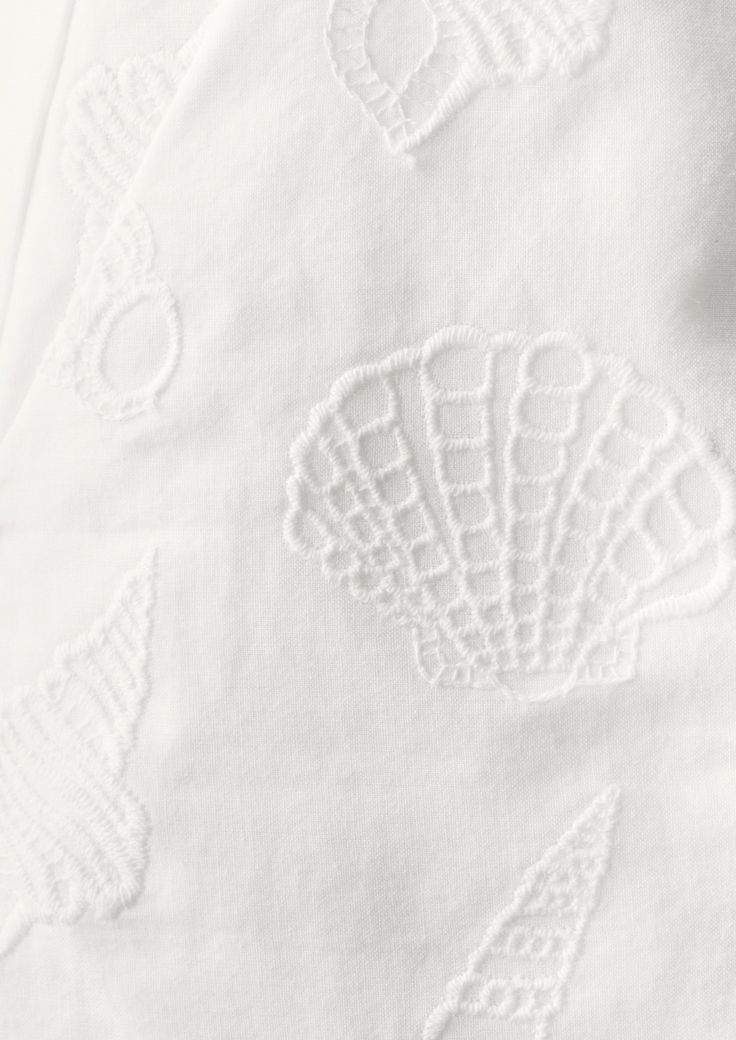 an embroidered white sheet with shells on it