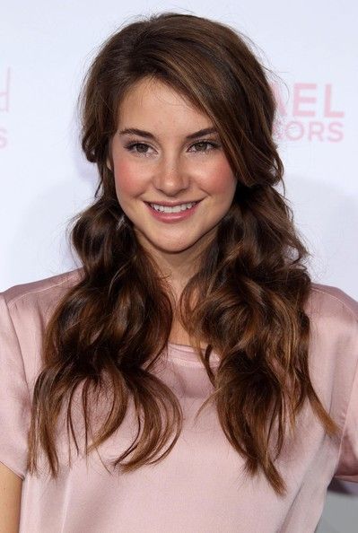 a woman with long brown hair smiling at the camera and wearing a pink shirt on