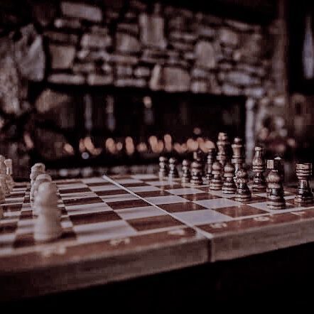 a chess board with several pieces on it and a fireplace in the backround