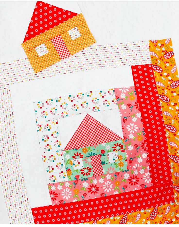 a close up of a patchwork quilt with a house on the front and small houses on the back