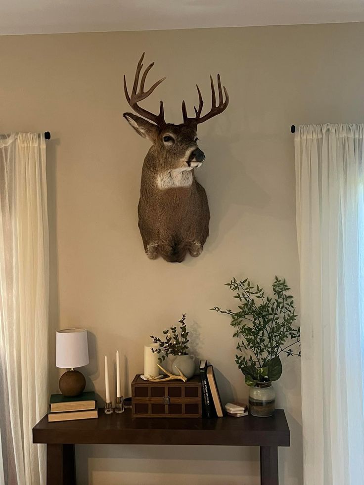 a deer head mounted on the wall above a table with books and candles in front of it