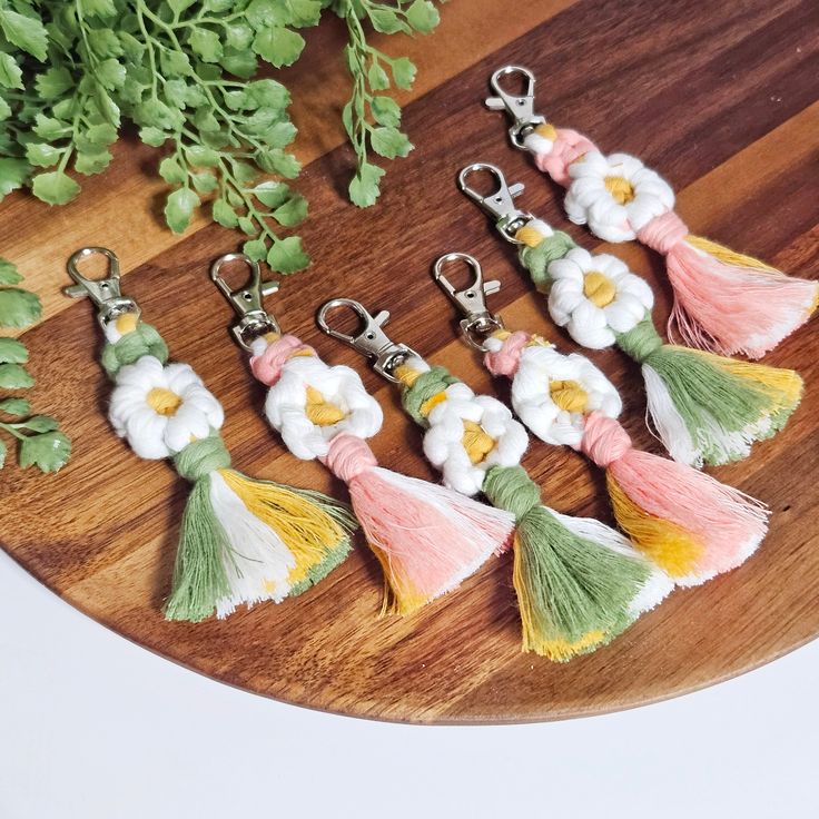 six tasseled key chains with flowers and leaves on them sitting on a wooden surface