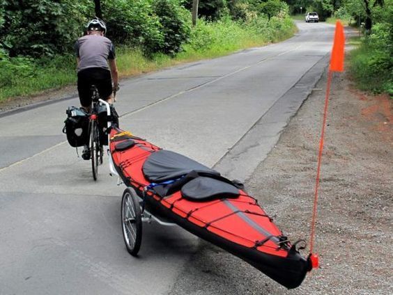 a man riding a bike with a kayak attached to it