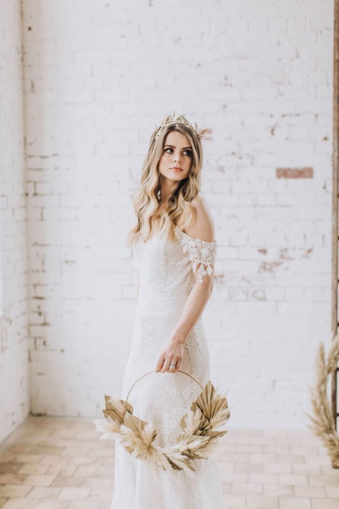 a woman in a white wedding dress holding a basket with flowers on it and wearing a flower crown