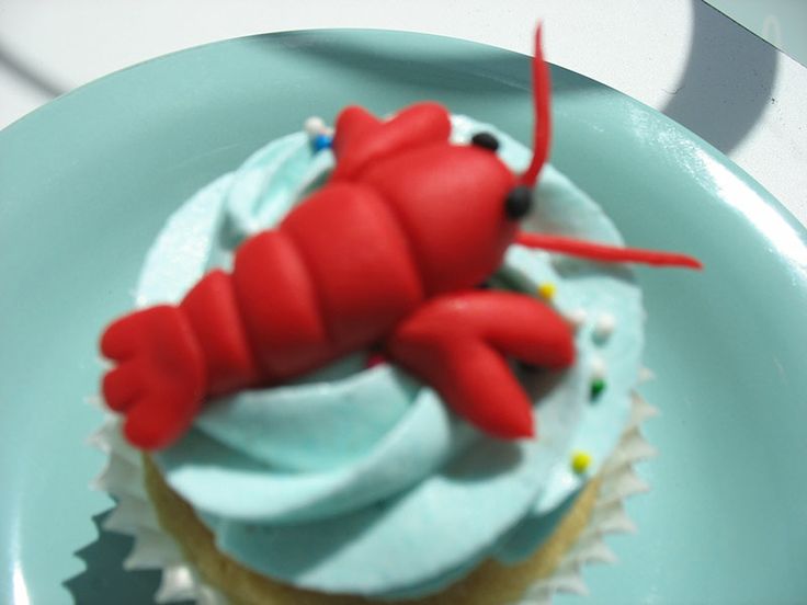 a cupcake with blue frosting and a red lobster on top