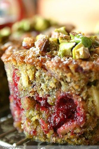 a close up of a piece of cake on a cooling rack with nuts and cranberries