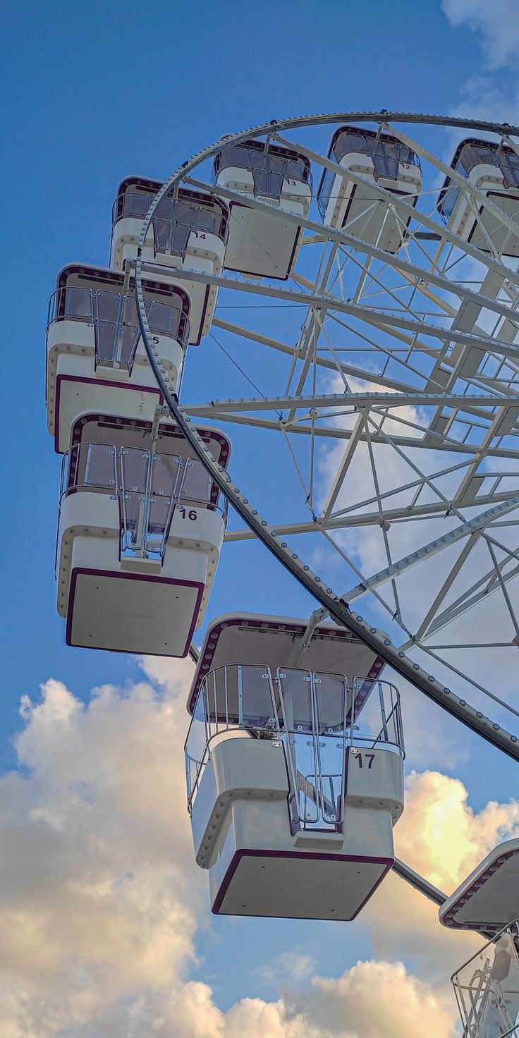 a ferris wheel is shown against a blue sky with clouds in the foreground,