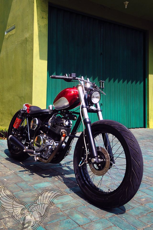 a red motorcycle parked in front of a green building