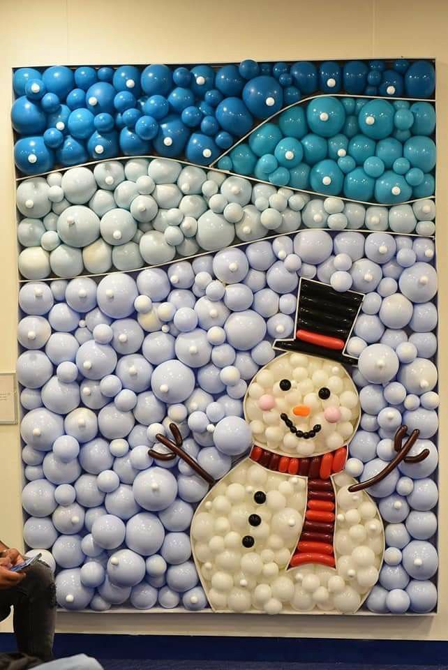 a snowman made out of plastic balls on display in a room with blue and white balloons