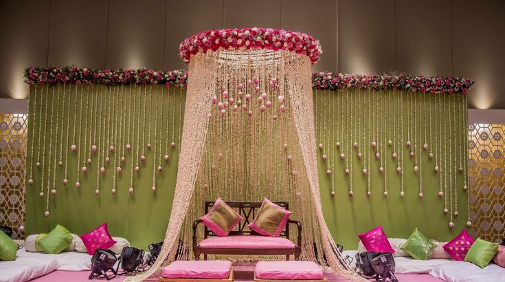 a decorated stage set up for a wedding with pink and green decor on the walls