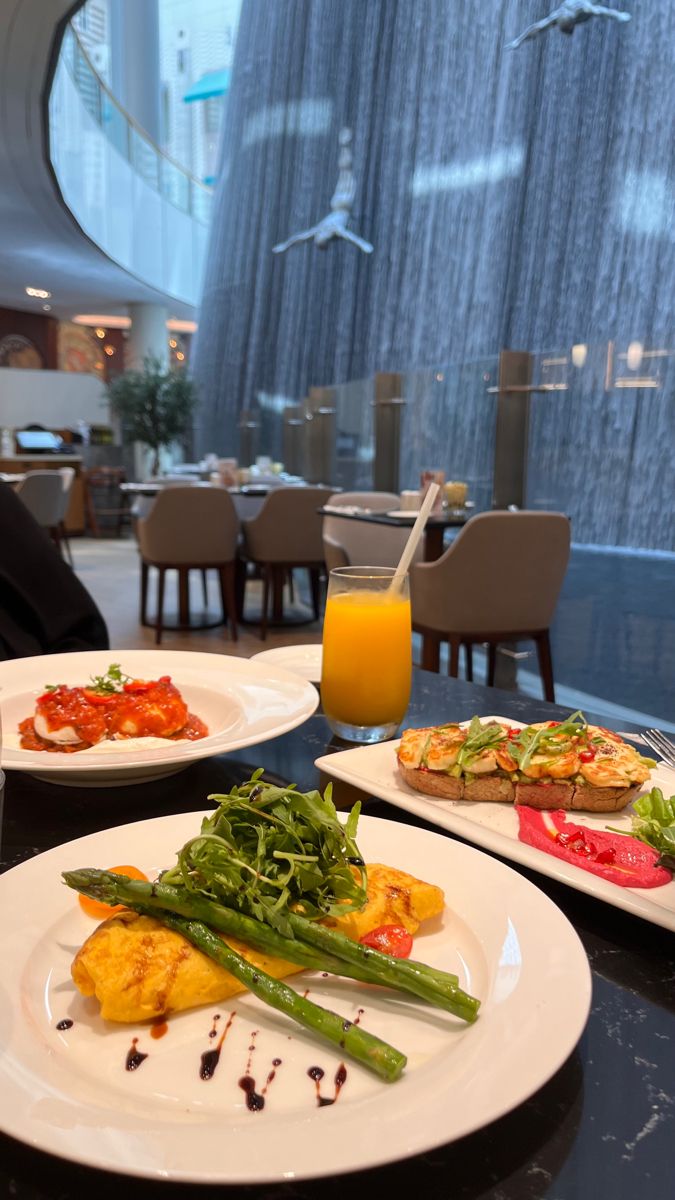 three plates with food on them sitting on a table in front of a glass window