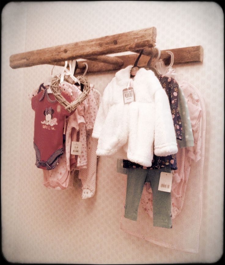 baby clothes are hanging on a wooden rack