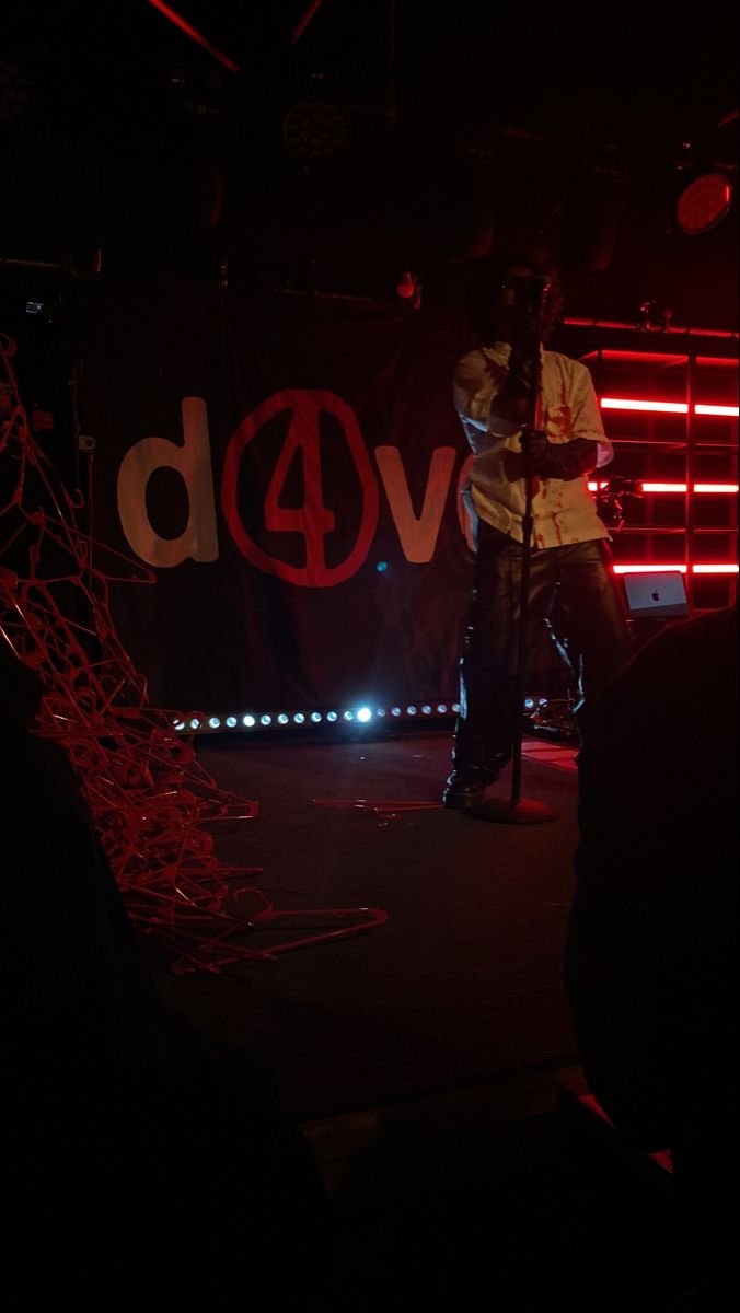 a man standing on top of a stage next to a red and black sign with the word vod