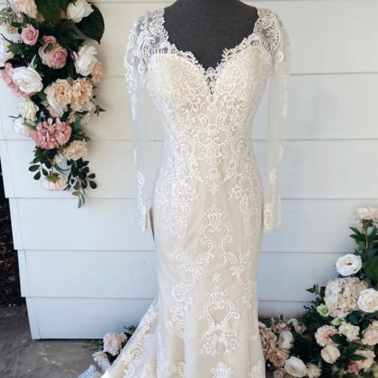 a wedding dress on display with flowers in the background