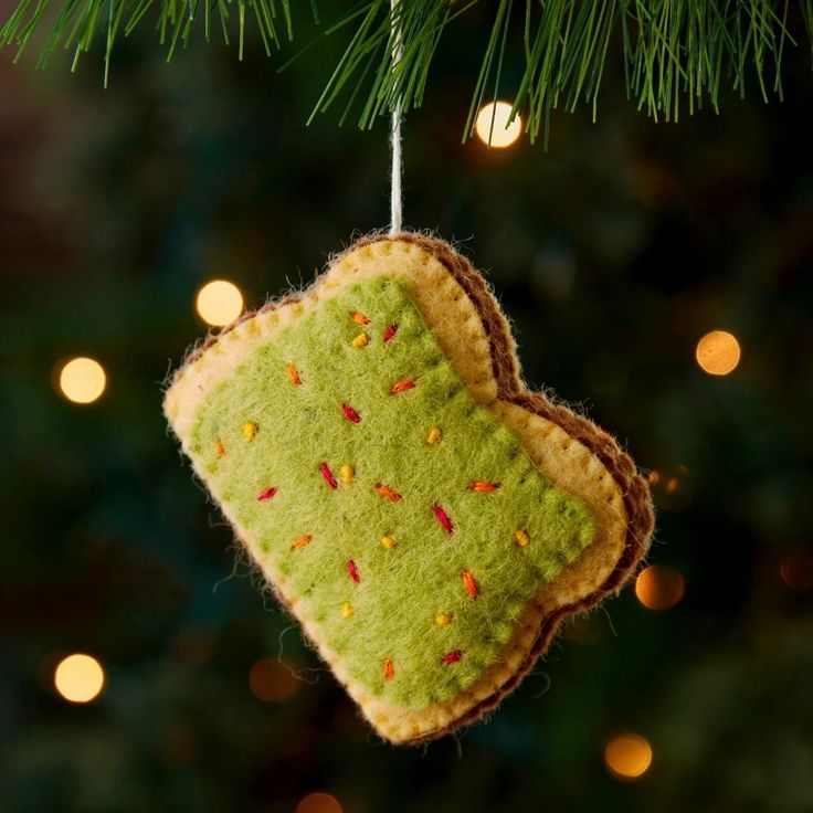 an ornament hanging from a christmas tree decorated with green and orange felt hearts