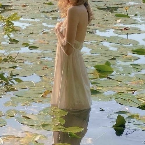 a woman is standing in the water with lily pads