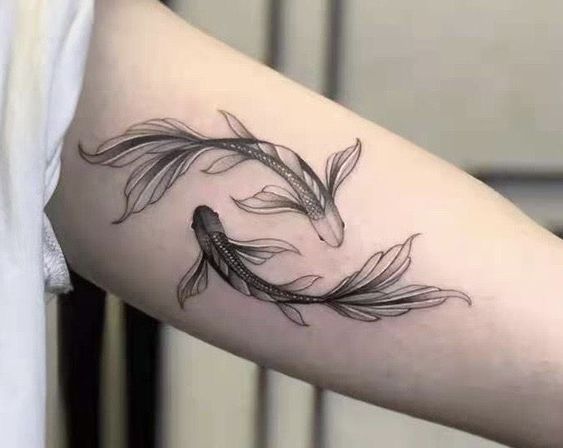 a woman's arm with two goldfish tattoos on it