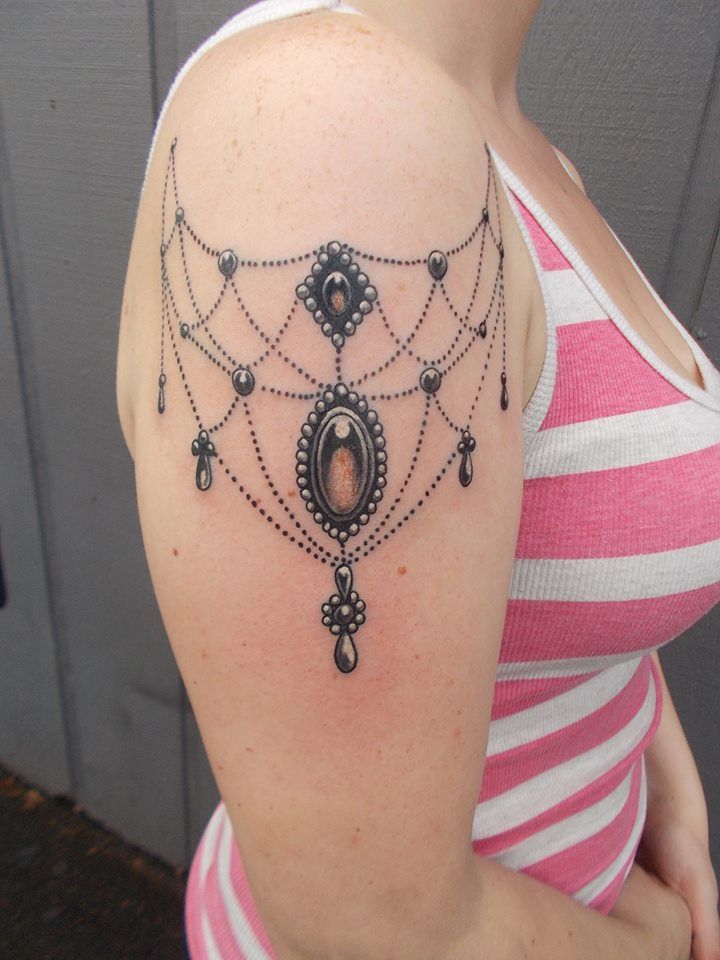 a woman wearing a pink and white striped shirt has a tattoo on her shoulder that is decorated with black beads