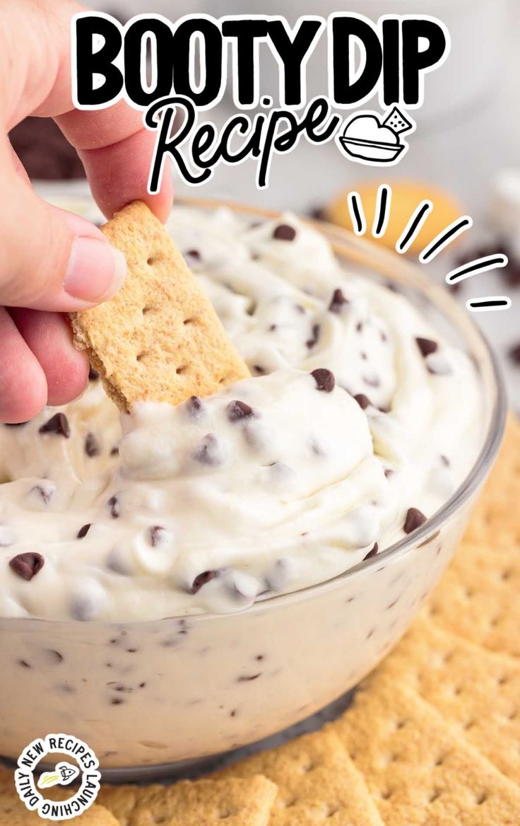 a hand dipping a cracker into a bowl of ice cream with chocolate chips on top